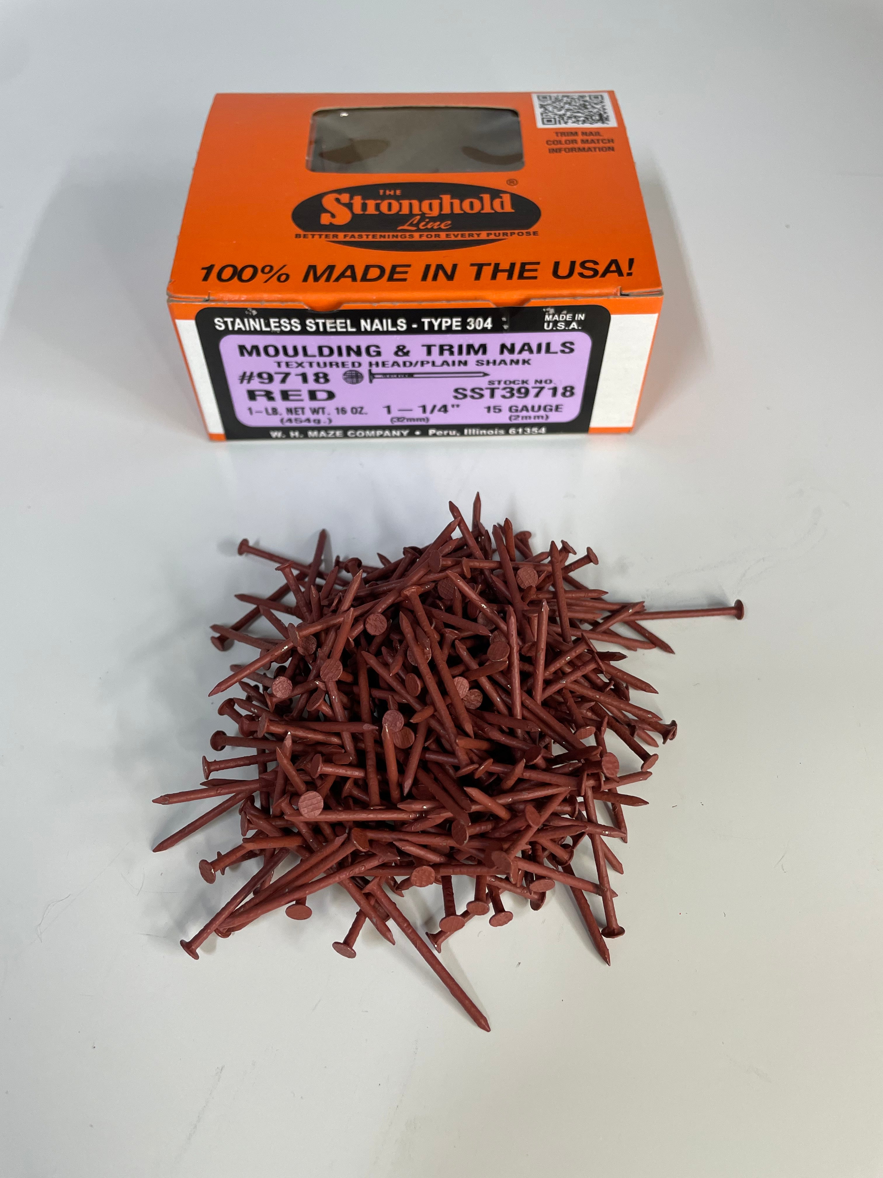 A box of Stainless Steel Trim Nails with a pile of loose nails in front of it. The nails are Lighthouse Red in color.