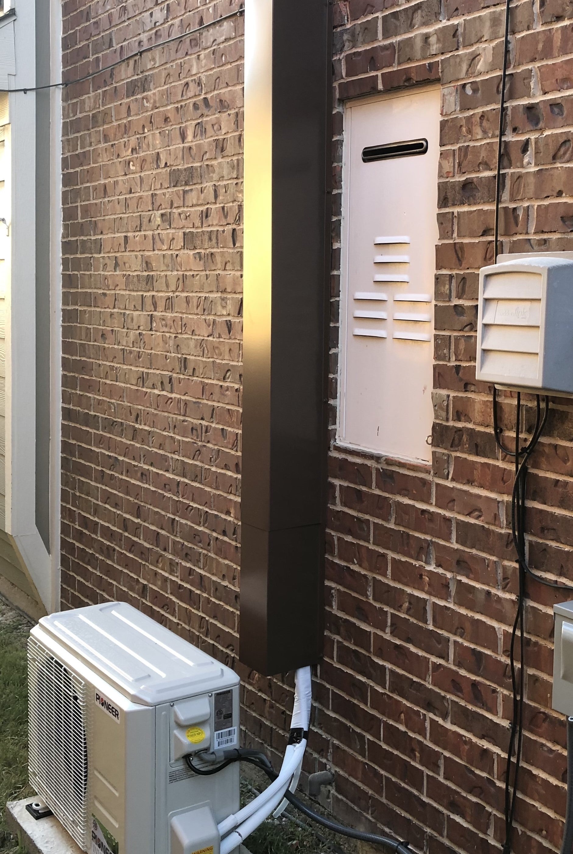 A brown Line Set Cover installed over a mini split HVAC unit.