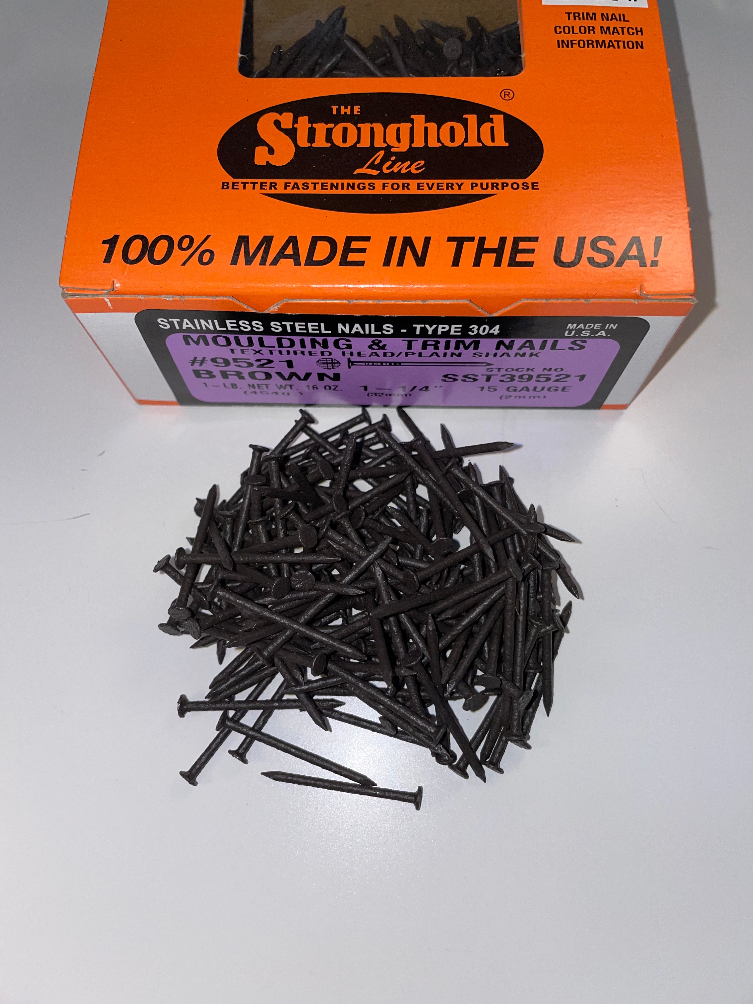 A box of Stainless Steel Trim Nails with a pile of loose nails in front of it. The nails are Musket Brown in color.