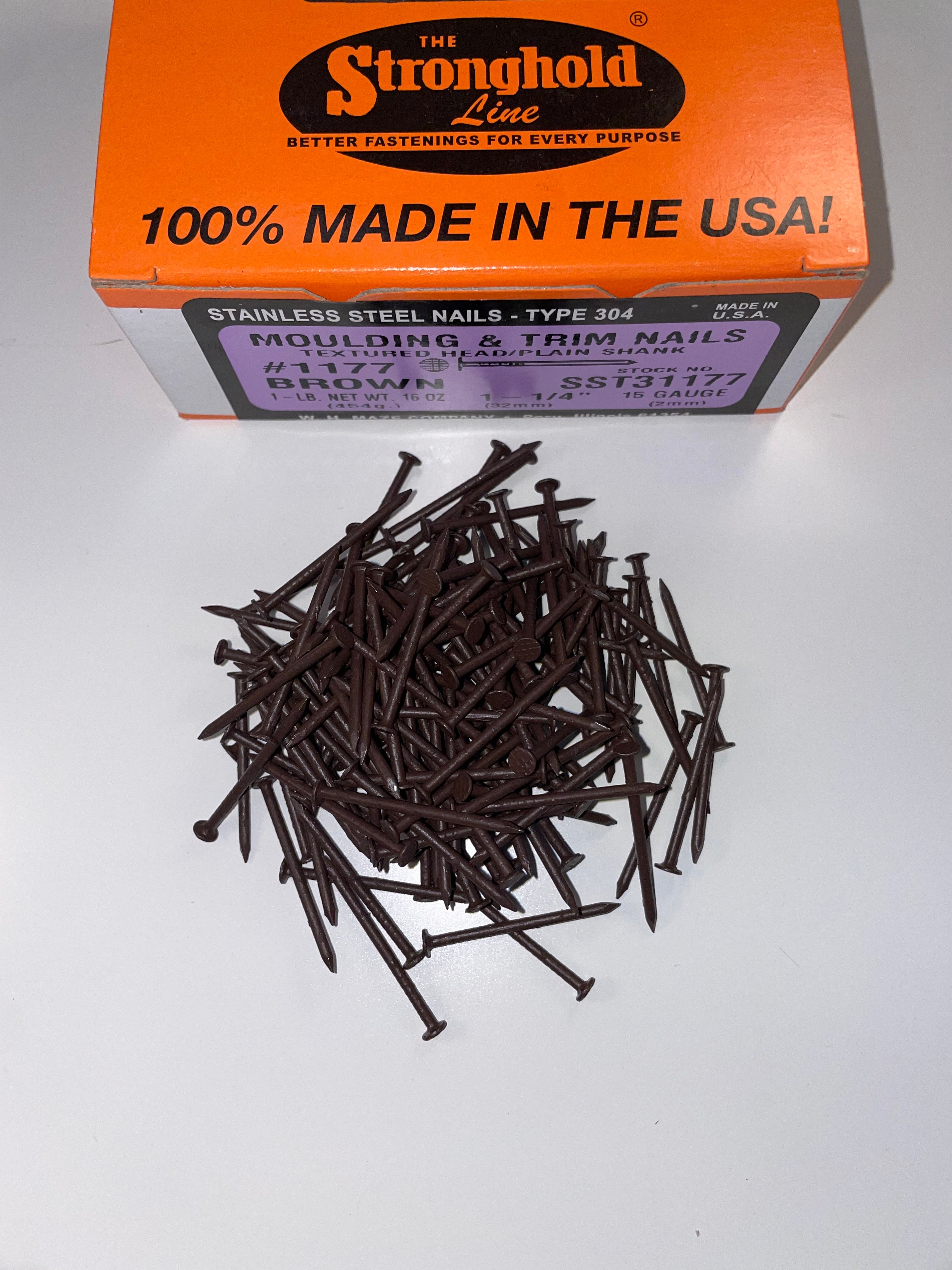 A box of Stainless Steel Trim Nails with a pile of loose nails in front of it. The nails are Royal Brown in color.