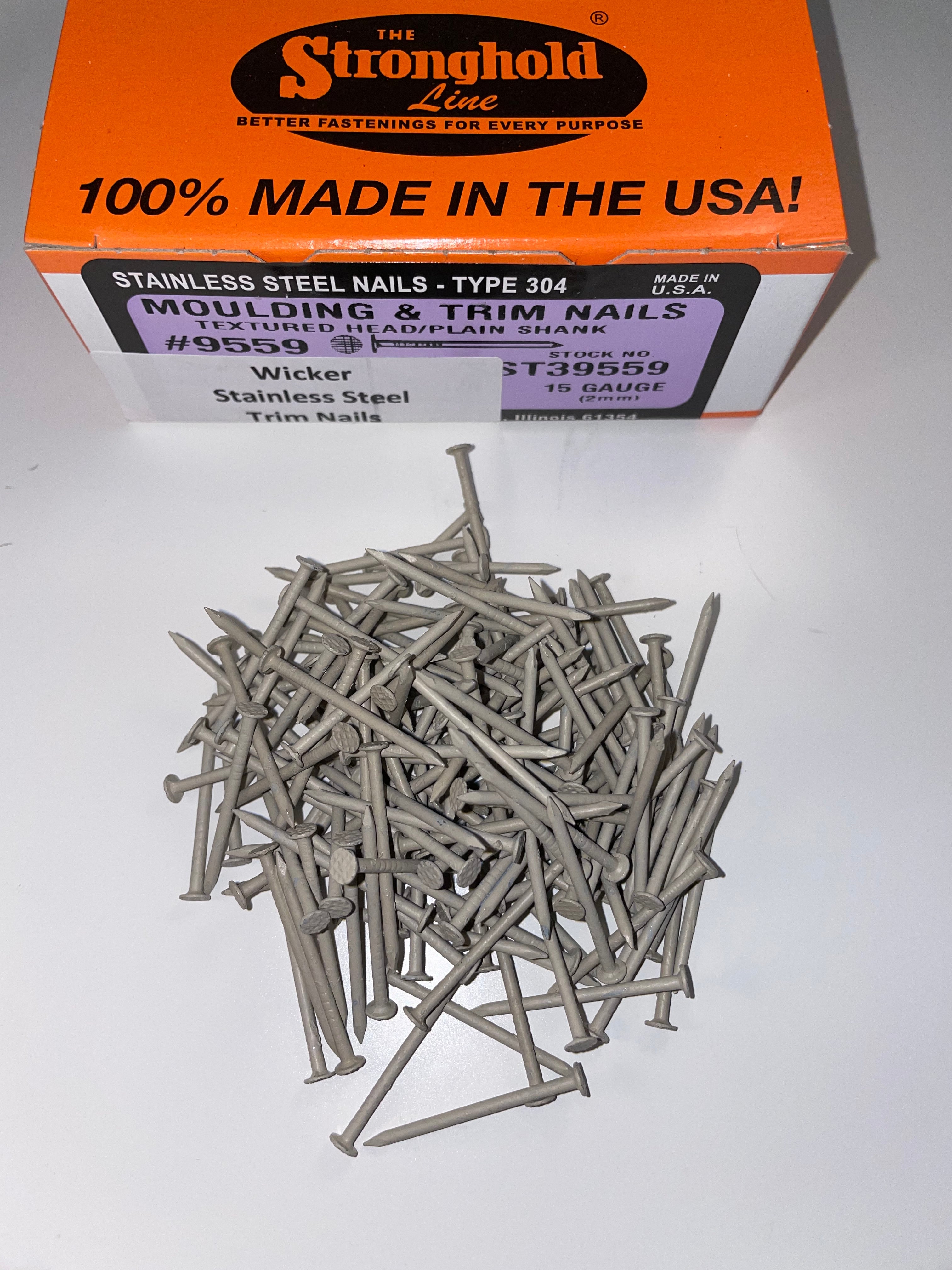 A box of Stainless Steel Trim Nails with a pile of loose nails in front of it. The nails are Wicker in color.